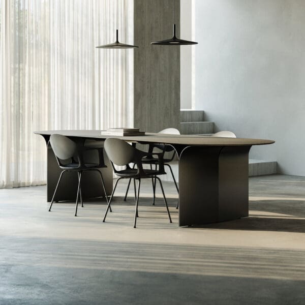 Image of Arcs minimalist dining table and Sepia armchairs by Joli, in room with long shadows on the floor