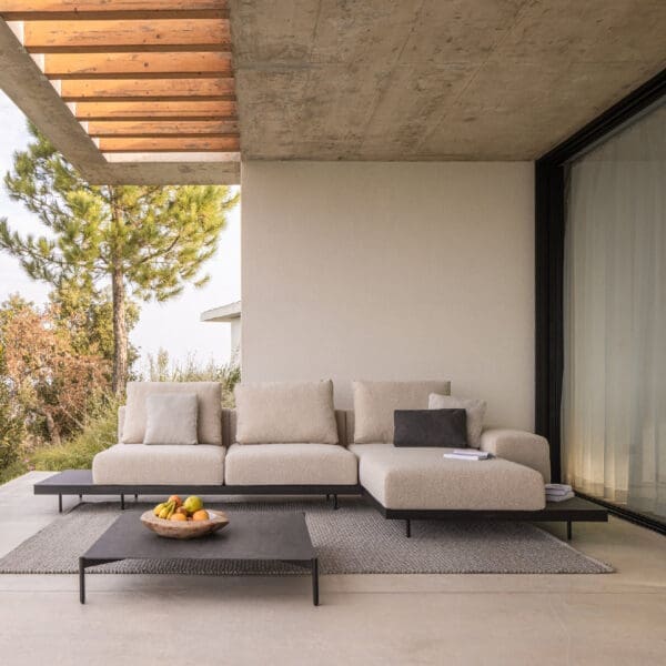 Image of Dongo chaise longue and sectional sofa shown on poured concrete terrace beneath cantilevered ceiling