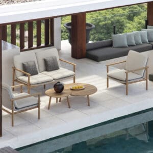 Image of Benoa teak garden sofa and lounge chairs on poolside next to still waters of swimming pool