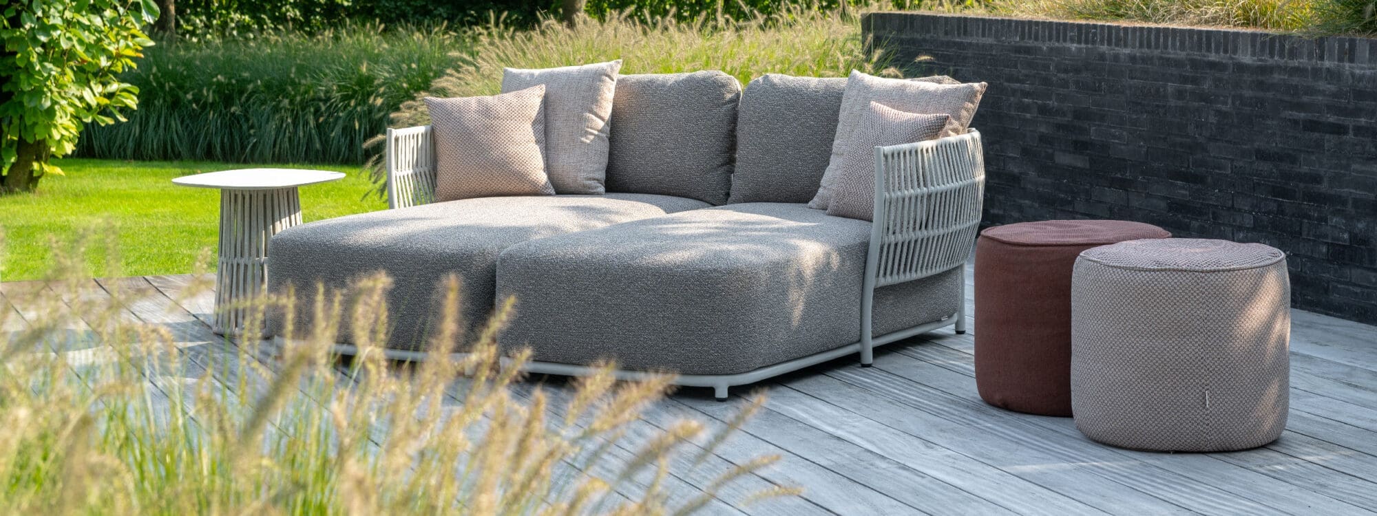 Image of pair of Jati & Kebon Cala daybeds placed together on decking, surrounded by grasses