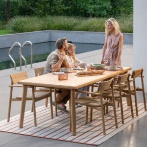 Image of couple and a child chatting around Lynn modern teak dining furniture by Jati & Kebon.