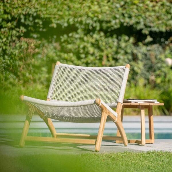 Image of Koozy teak garden easy chair with rope seat & back, shown on poolside with verdant hedging in the background