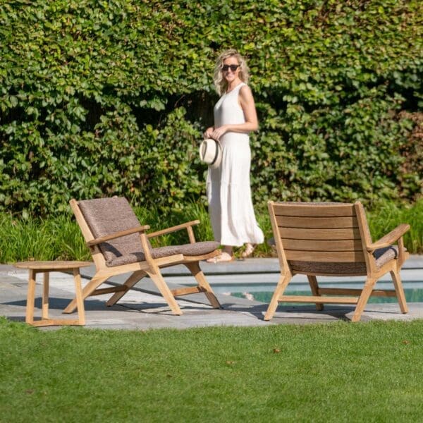 Image of woman walking past a couple of Koozy teak lounge armchairs