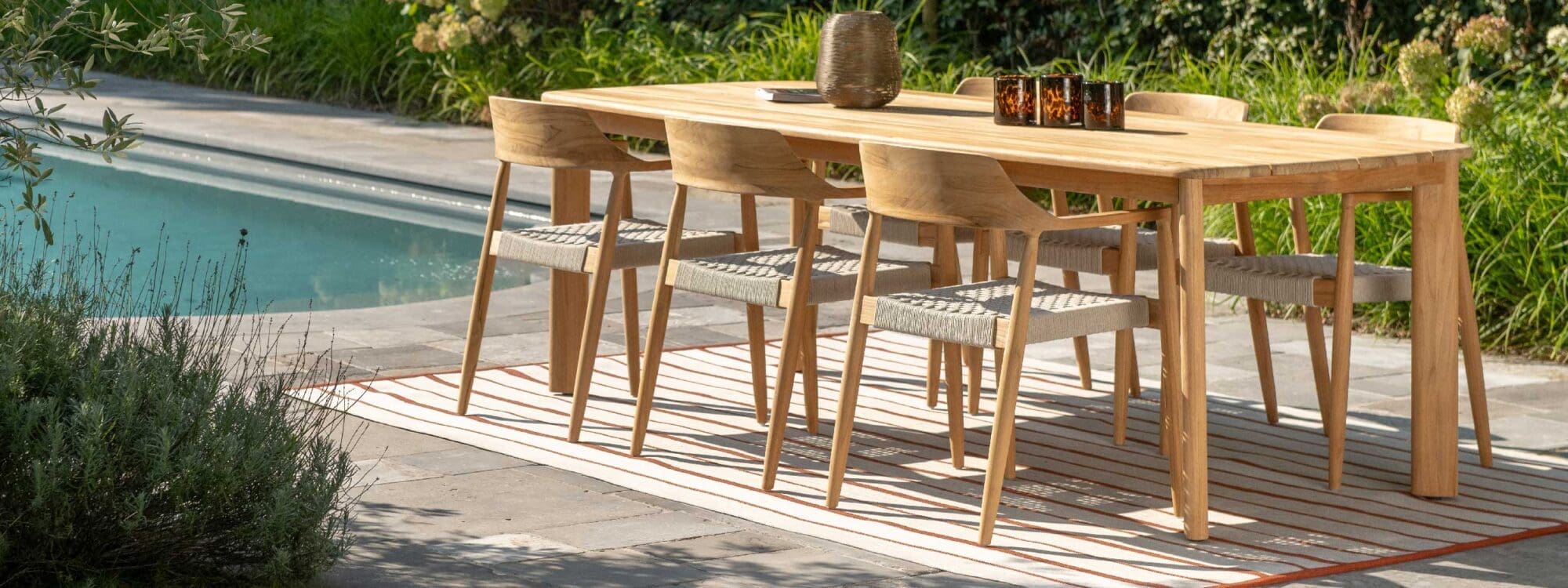 Image of Tofino teak garden dining set on decking, with still waters of swimming pool in the background