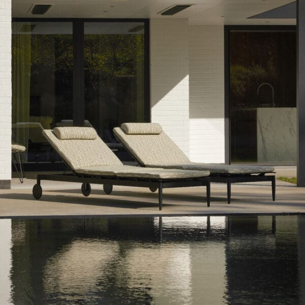 Image of pair of Marguerite sun loungers reflecting in the still waters of a swimming pool