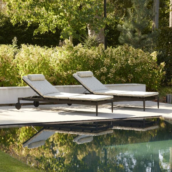 Image of pair of Marguerite sun loungers on poolside surrounded by greenery