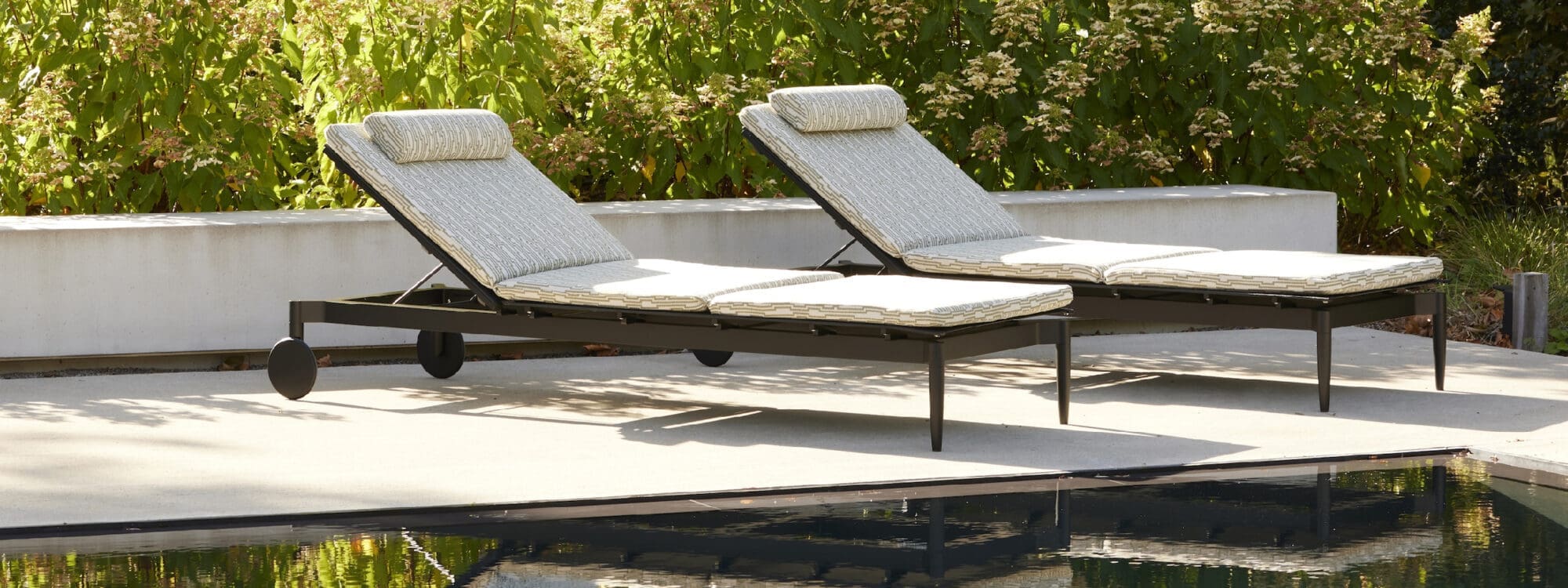 Image of pair of Joli Marguerite sun loungers with dark aluminium frames and cream coloured cushions