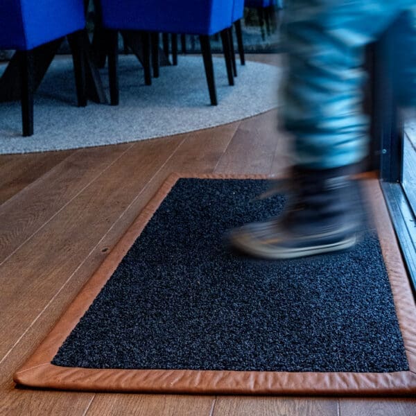 Image of person wiping their feet on RiZZ indoor mat with natural leather border