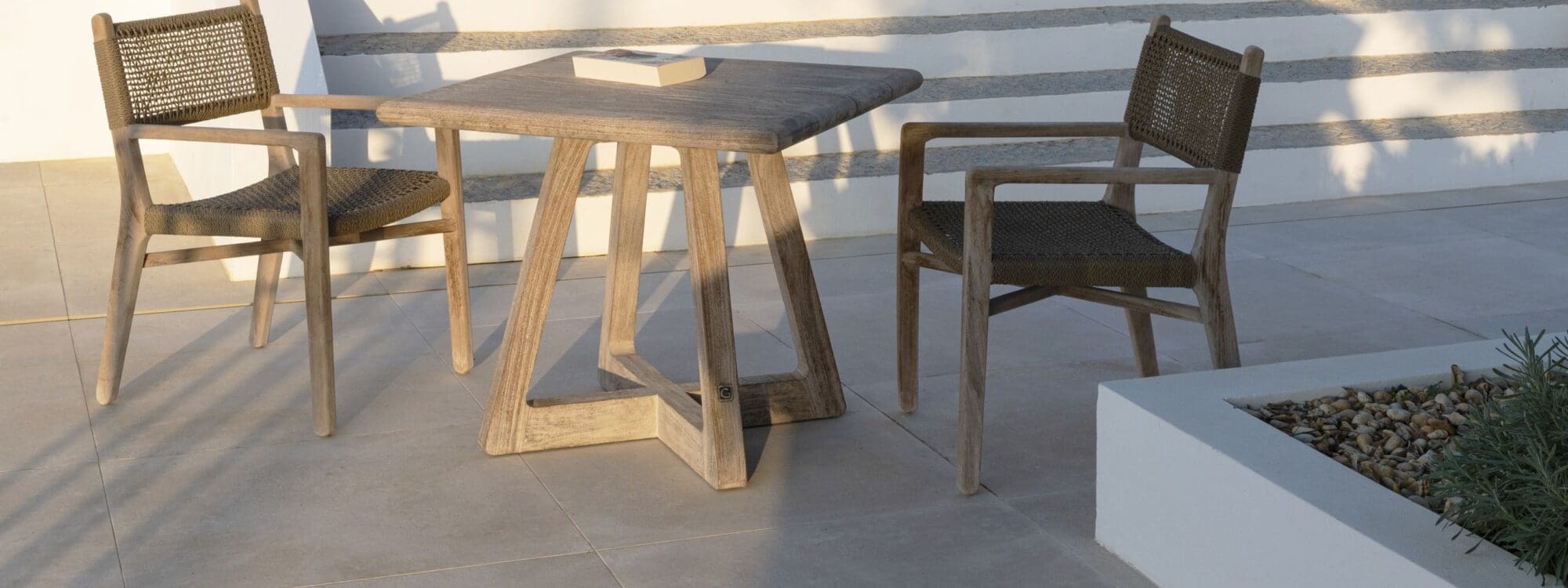 Image of pair of Fiona teak armchairs placed around Dennis square teak dining table by Gommaire