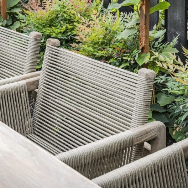 Image of Carlo low chair's rope back and arms, next to Carlo teak dining table by Gommaire