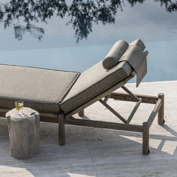 Image of Gommaire Mieke teak sunbed with deep full-length cushion next to still reflective waters of a swimming pool