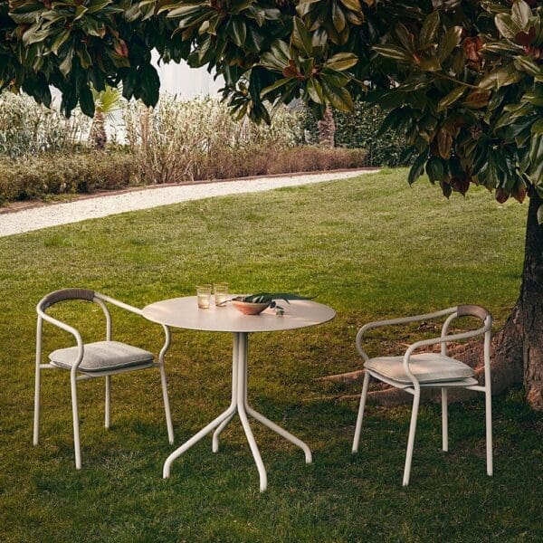 Image of Unopiu Salo bistro table and chairs in Sand colour, shown on verdant grass lawn