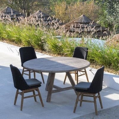 Image of Anton solid teak circular dining table surrounded by Gommaire dining chairs