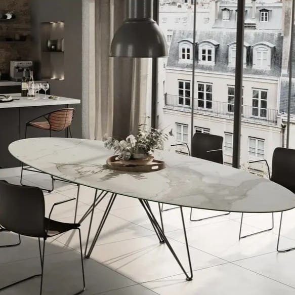 Image of Joli Wire ellipse dining table with fin de siecle buildings outside the window