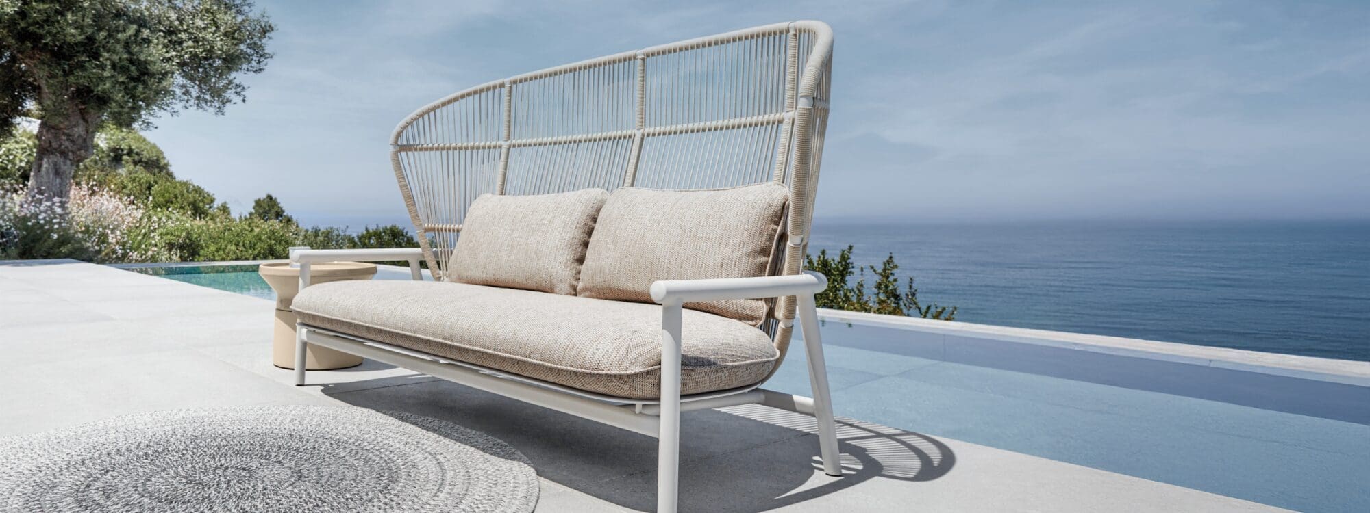 Image of Gloster Fern 2 seat aluminium sofa with high back on sunny poolside