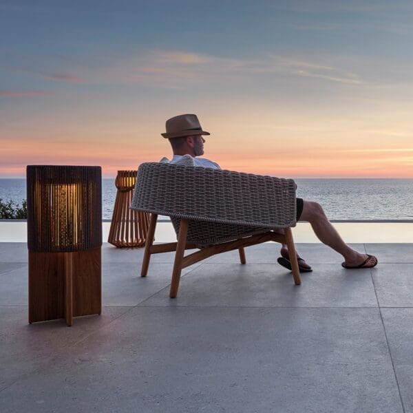 Image of man sat in Gloster Wrap lounge chair on terrace at dusk