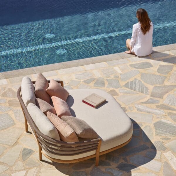 Image of Royal Botania Archy Lounge daybed on poolside with a woman sat on edge of pool in the background